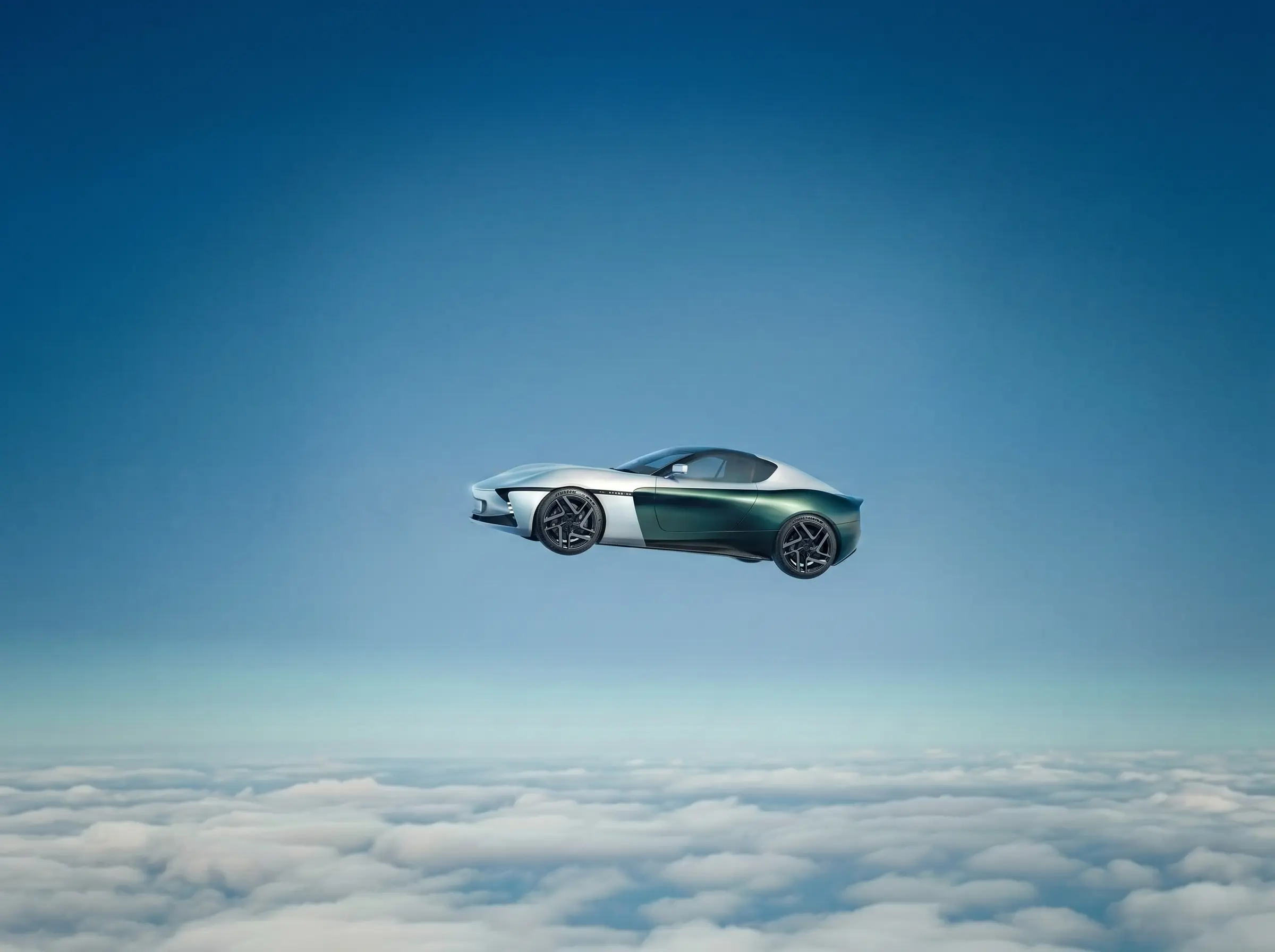 Roadster in profile above an unbroken layer of cloud